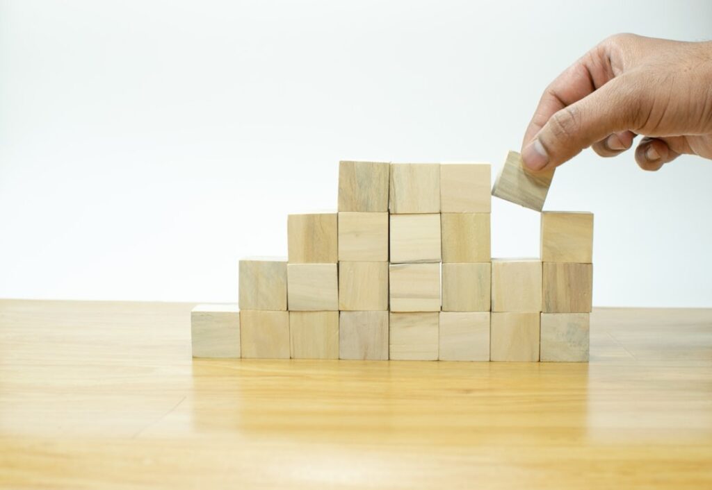 someone building blocks using little cream block to make a wall